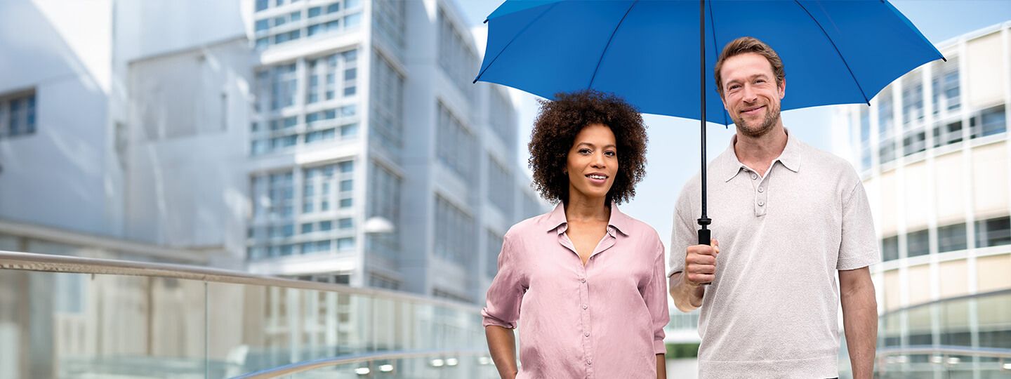 Lächelnde Frau und Mann stehen unter einem blauen Schirm